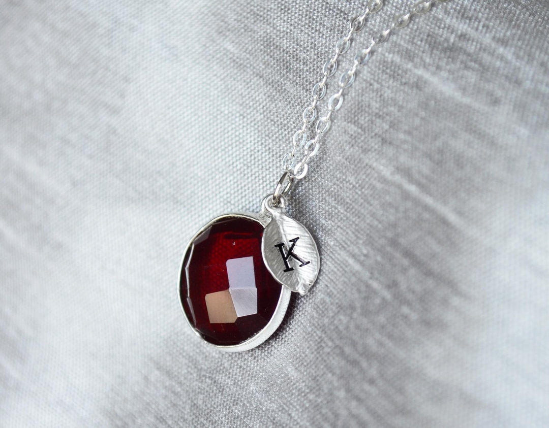 Necklace with a red pendant and a silver tag on a gray background