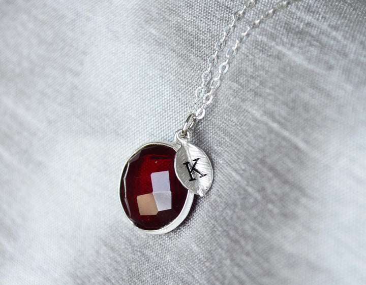 Necklace with a red pendant and a silver tag on a gray background