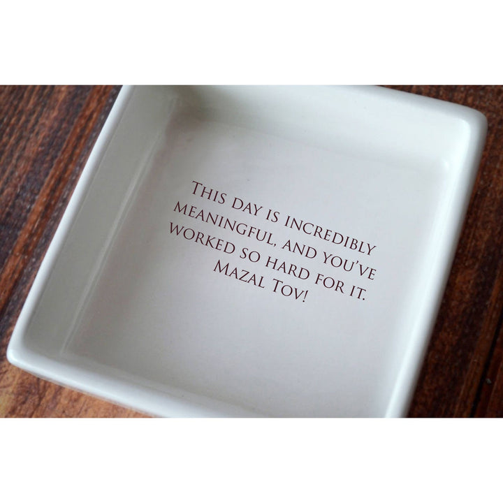 White ceramic dish with engraved text on a wooden surface