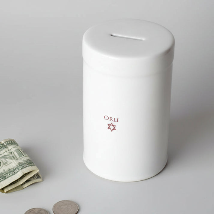White piggy bank with 'Orli' personalization with dollar bill and coins.