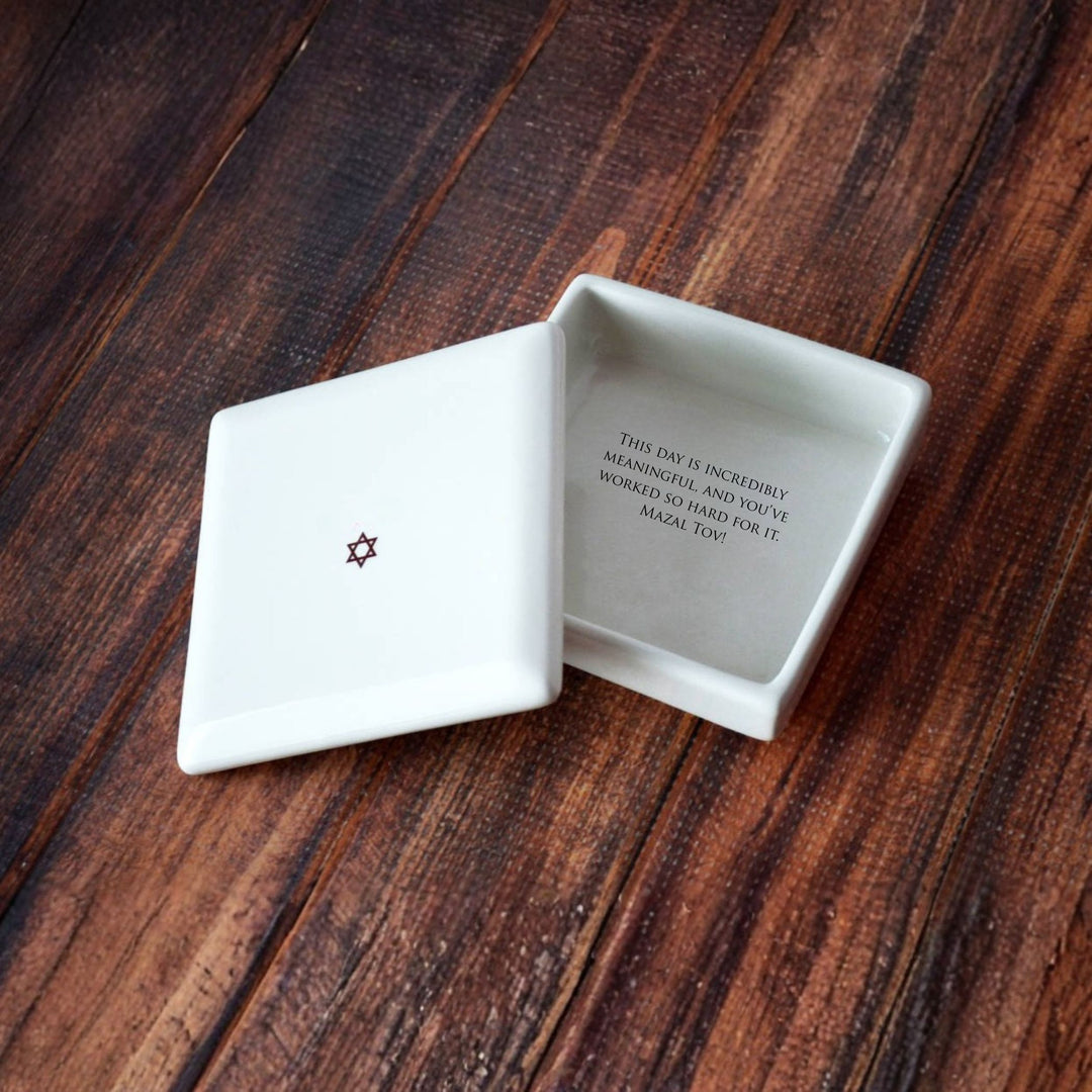 Open white ceramic box with text on a wooden surface