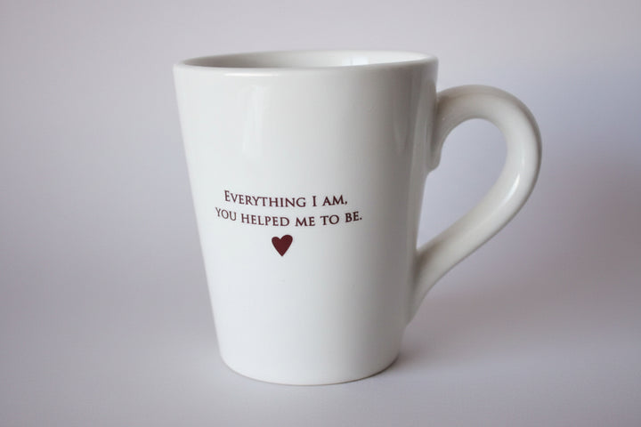White mug with text and heart on a gray surface