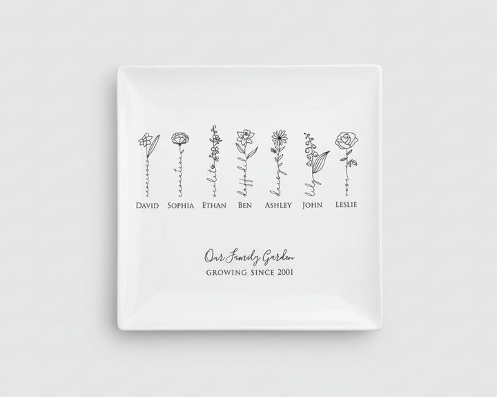 White square plate with black floral designs and names on a light gray background