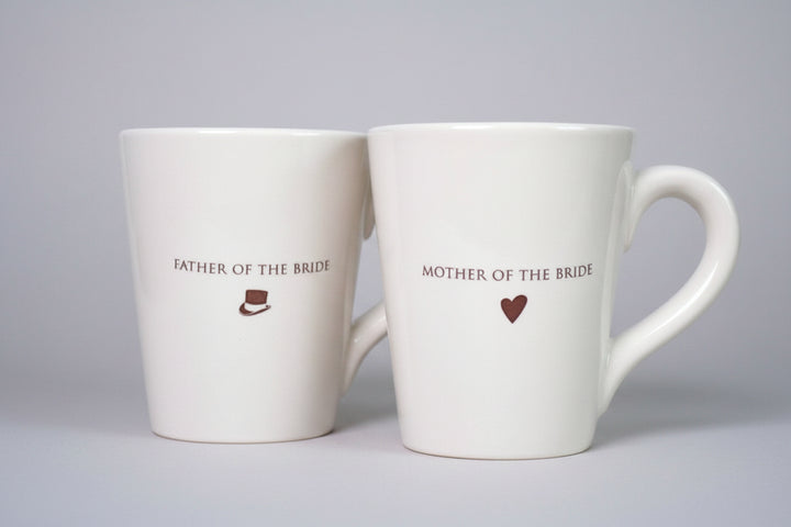 Two white mugs with 'Father of the Bride' and 'Mother of the Bride' text 
