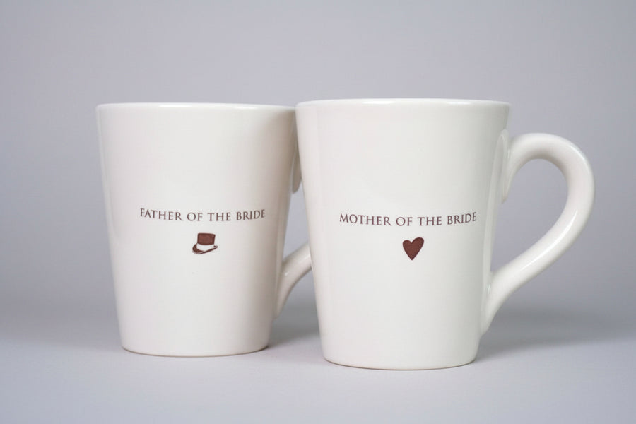 Two white mugs with 'Father of the Bride' and 'Mother of the Bride' text 