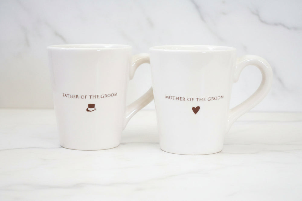 Two white mugs with 'Father of the Groom' and 'Mother of the Groom' text