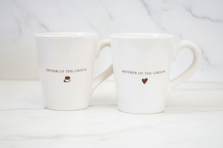 Two white mugs with 'Father of the Groom' and 'Mother of the Groom' text