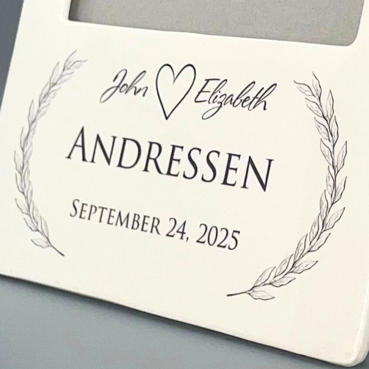 Personalized picture frame with 'John' and 'Elizabeth', heart symbol, and 'Andressen' on a decorative background.