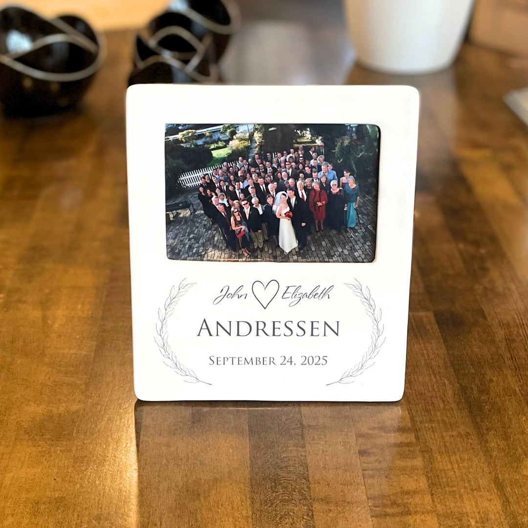 White photo frame with a printed wedding photo on a wooden surface. personalized wedding theme