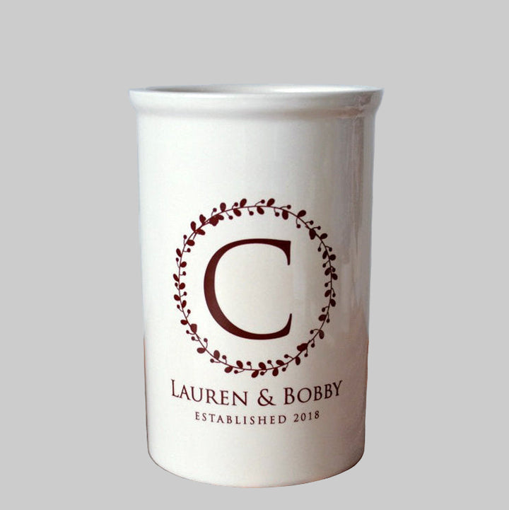 White mug with brown letter 'C' and text on a wooden surface with chevron patterned background