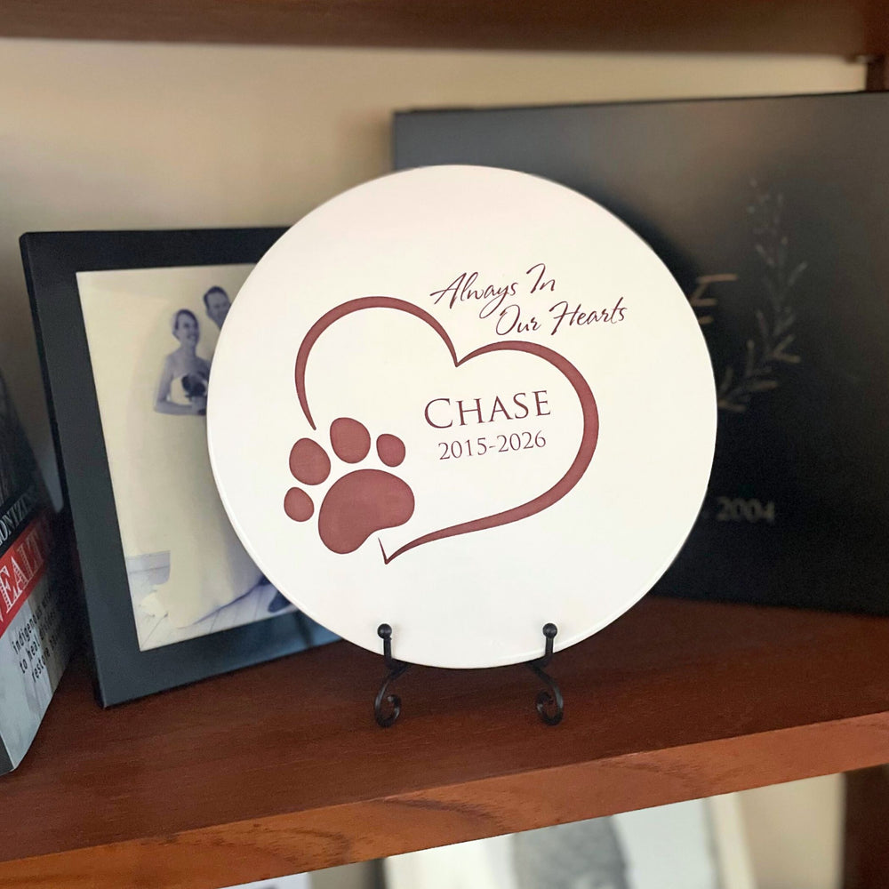Memorial plaque for a pet named Chase on a wooden shelf with a photo frame in the background.
