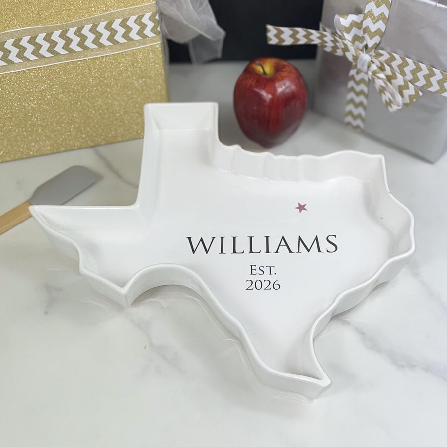 White Texas-shaped dish with 'Williams' and 'Est. 2026' text, placed on a light surface with decorative elements.
